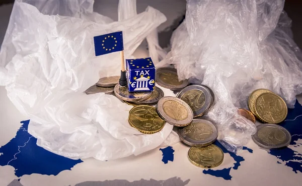 Mapa de la UE con monedas en euros y una bolsa de plástico que simboliza la regulación fiscal europea del plástico . — Foto de Stock