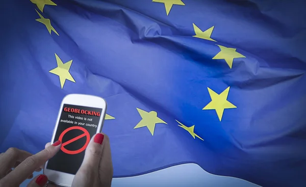 Manos femeninas usando un smartphone con bloqueo geográfico en pantalla. y bandera de la UE en segundo plano — Foto de Stock