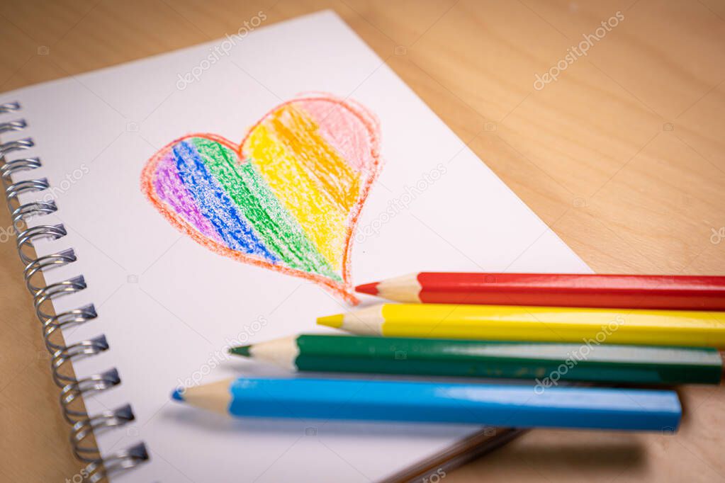 Heart with the colors of the LGTBI or GLBT flag on a blank notebook with rainbow pens