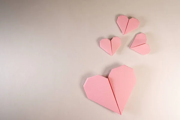 Corazones de origami rosados sobre un fondo de papel — Foto de Stock