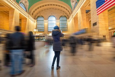 Woman taking a photo in the main lobby of Grand Central Station in New York. clipart