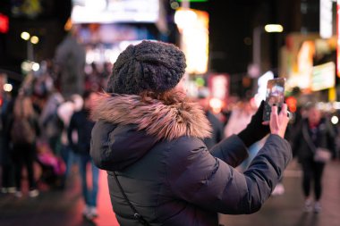 Güzel kıvırcık esmer kadın Times Meydanı, New York 'ta akıllı telefonuyla selfie çekiyor..
