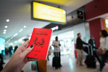Havaalanında elinde Singapur pasaportu olan bir kadın var.