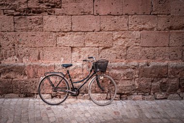 Eski bir taş duvarın önünde siyah bisiklet