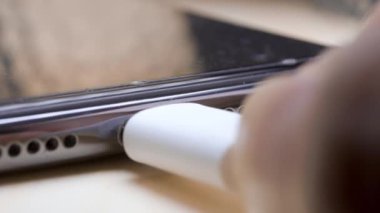 Man plugging in white USB Type C cable into USB-C port on smartphone