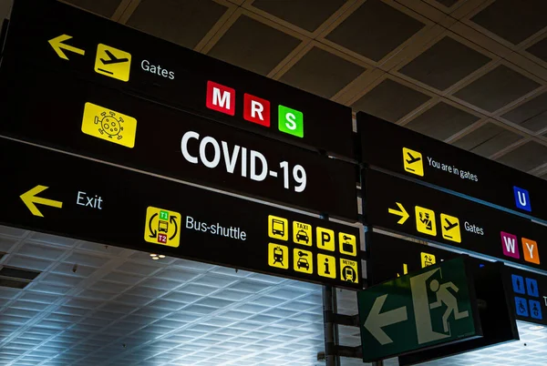 Informasjonstavle med Covid-19-ord om den på en internasjonal lufthavn . – stockfoto