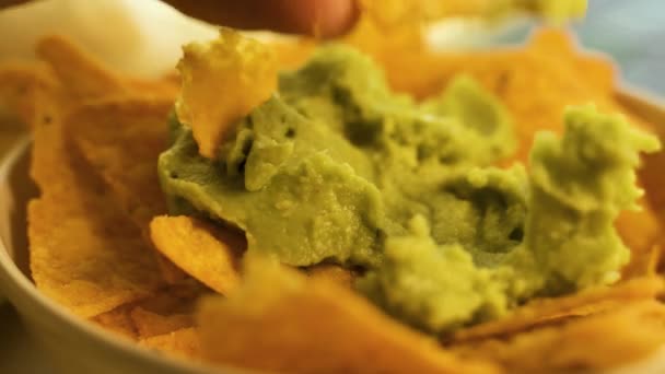 Mano sumergiendo un chip de nacho en un tazón de guacamole recién hecho . — Vídeo de stock