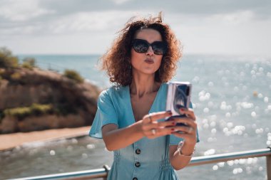 Tourist woman in summer dress and sunglasses taking a selfie