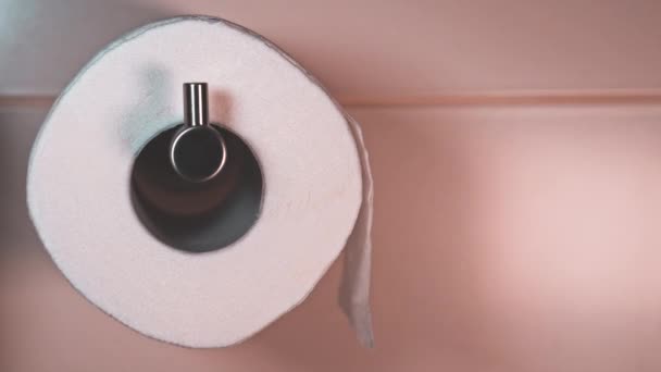 Macro view of a roll of white toilet paper in a tiled bathroom — Stockvideo