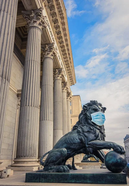 Estatua de león de bronce frente al Parlamento español con máscara quirúrgica —  Fotos de Stock