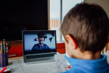 Çocuk evde online dersi sırasında ödev çalışıyor.