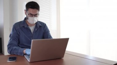 Yüz maskeli ve mavi eldivenli adam telefonu kaldırıyor.