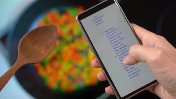 Человек использует скользящий палец на экране телефона подготовки к приготовлению пищи, следуя рецепт приготовления онлайн — стоковое видео