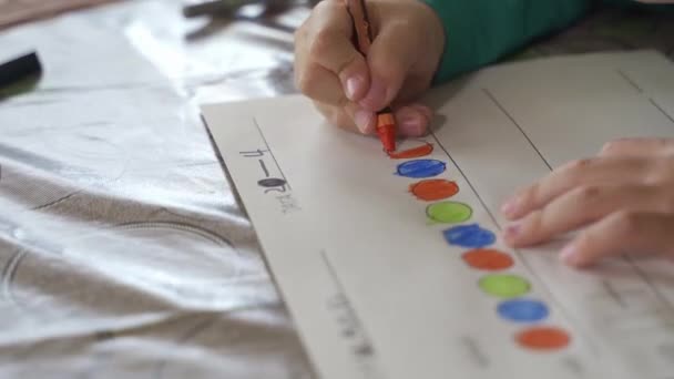 Close-up view of a child drawing with crayons on paper or doing homework from home — Stock Video