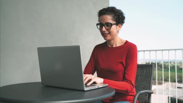 Távoktatás a karantén alatt. Egy nő dolgozik egy laptopon az erkélyen. Szabadúszó, távoli munka. — Stock videók