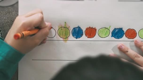 Kind zeichnet mit Buntstiften auf Papier oder erledigt Hausaufgaben von zu Hause aus — Stockvideo