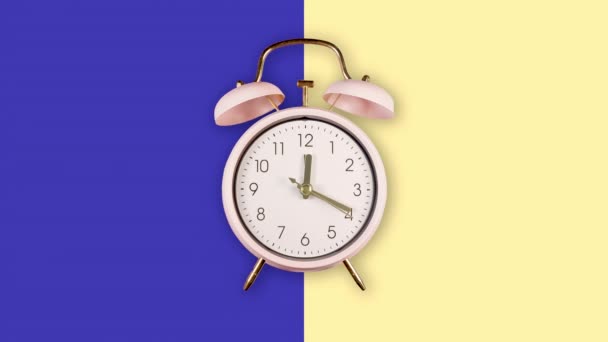 Звонящий двойной колокольчик винтажный классический будильник Изолированный на темно-синем и желтом пастельных красочных фоне — стоковое видео