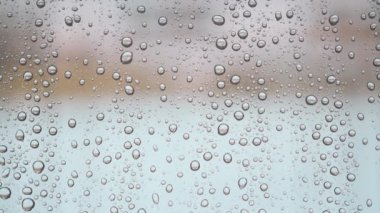 Bulutlu arkaplan ile pencere camları üzerine yağmur damlaları