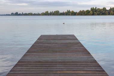 Wooden pier at lake in the early morning clipart