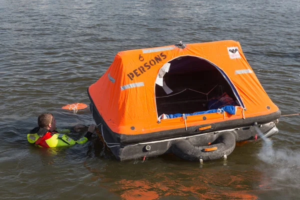 Trabajador de rescate mostrando balsa salvavidas en el puerto de Urk, Países Bajos — Foto de Stock
