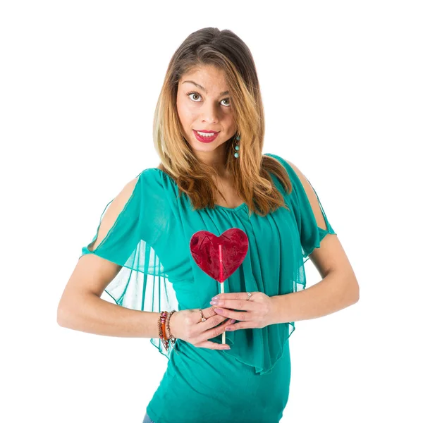 Beautiful woman holding red heart-shaped lollypop in front of her body — Stock Photo, Image