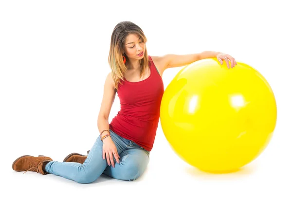 Frau sitzt mit großem gelben Ballon auf dem Boden — Stockfoto