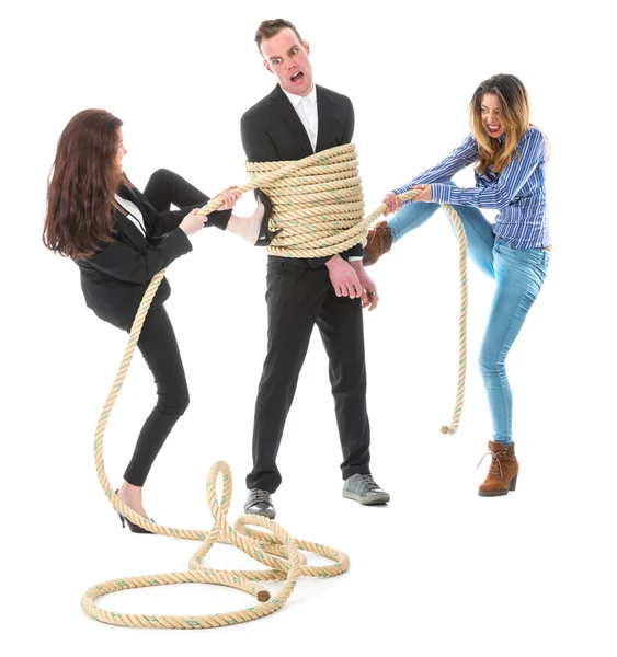 Two angry woman tying a business man with rope — Stock Photo, Image