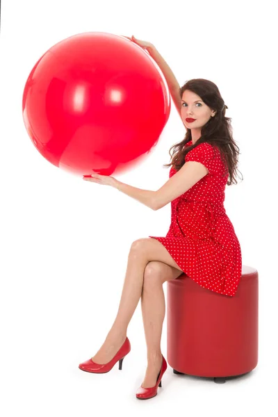 Mulher bonita sentada no banco de pés segurando grande balão vermelho — Fotografia de Stock