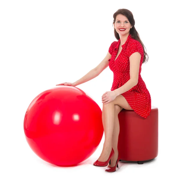Beautiful woman sitting on footstool holding big red balloon — Stock Photo, Image