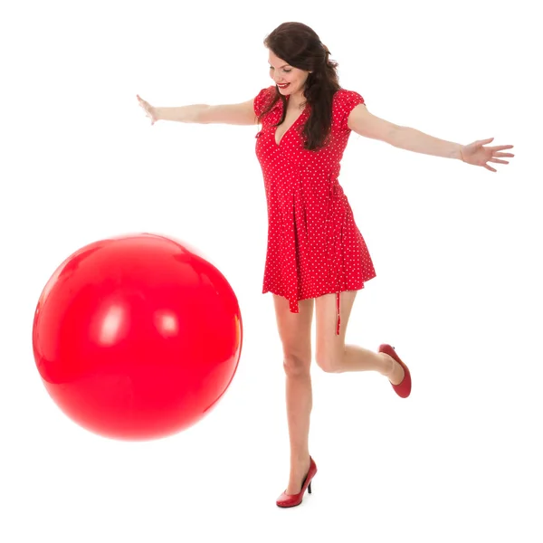 Schöne Frau im roten Kleid spielt mit einem großen roten Luftballon — Stockfoto