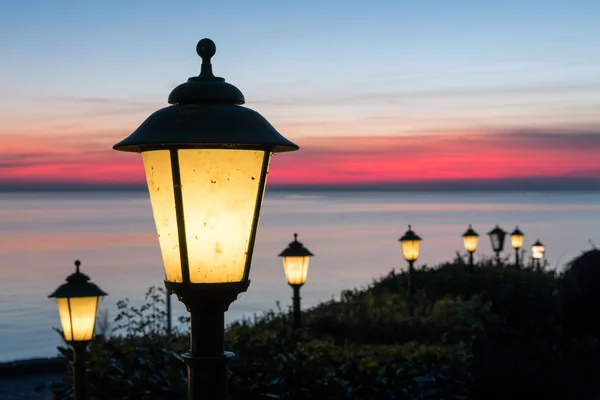 Lampioni lungo viale olandese con bel tramonto sul mare — Foto Stock