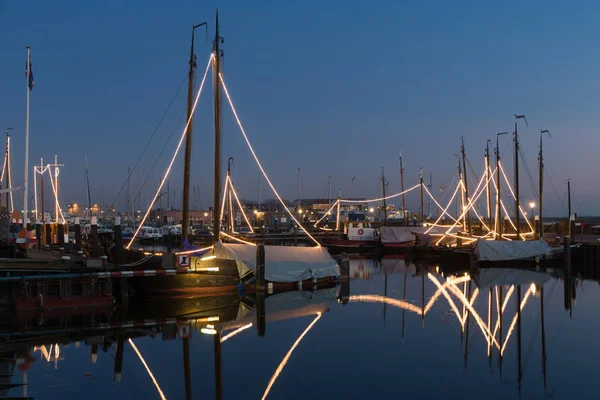 Illuminated traditional wooden fishing ships at night in Dutch harbor — Stock Photo, Image