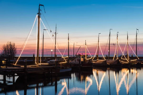 Illuminated traditional wooden fishing ships at night in Dutch harbor — Stock Photo, Image