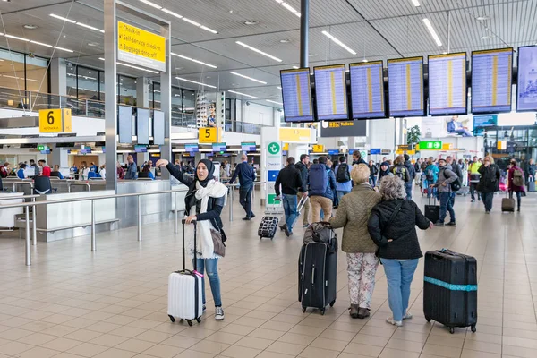Reizigers en vrouw met hoofddoek op Nederlands-Schiphol — Stockfoto