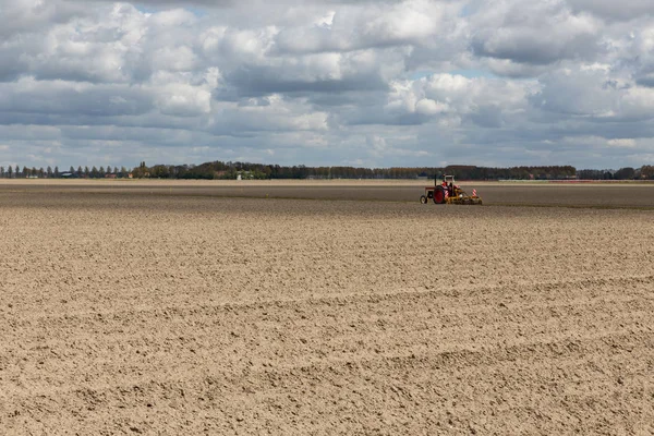 Paisagem holandesa com trator em campo arado no início da primavera — Fotografia de Stock