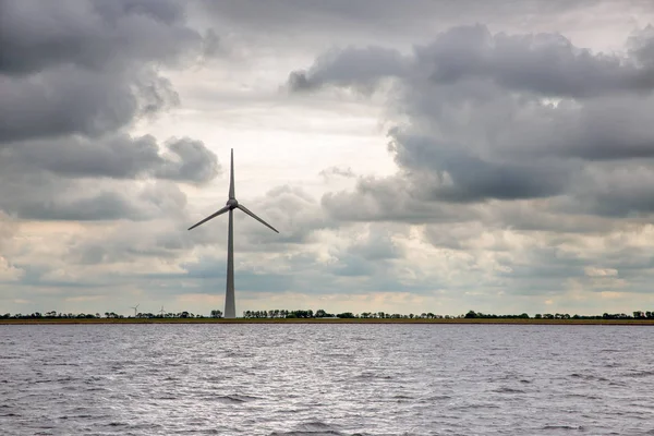 Turbina eólica na costa holandesa com céu escuro ameaçador — Fotografia de Stock