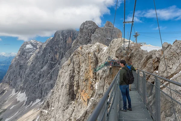 Österreichisches Dachsteingebirge mit Wanderern über eine Stahlseilbrücke — Stockfoto