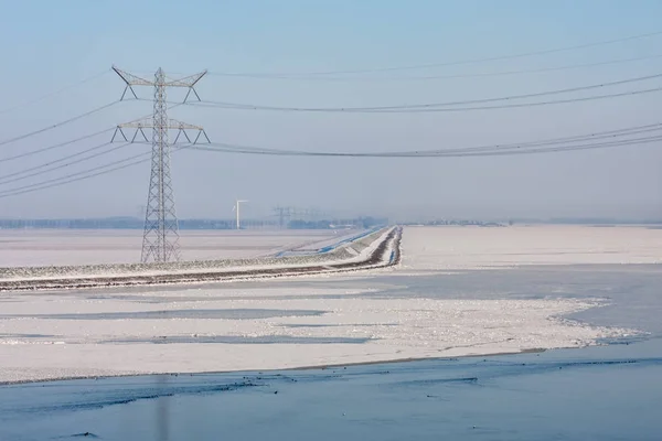 Frozen lake covered with haze and view at power pylon — Stock Photo, Image