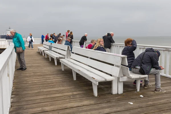 Mensen op houten pier Cuxhaven wachten voor de veerboot naar Helgoland. — Stockfoto