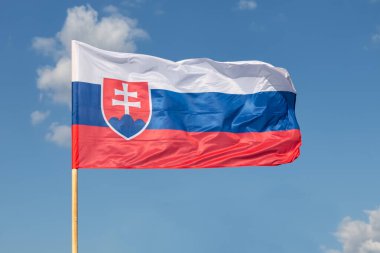 Mavi arka planda rüzgarda dalgalanan Slovakya ulusal bayrağı