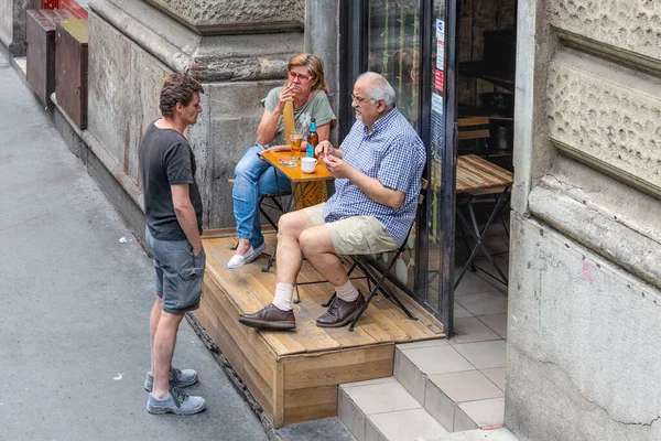 Personas sentadas frente a un café fumando un cigarrillo — Foto de Stock