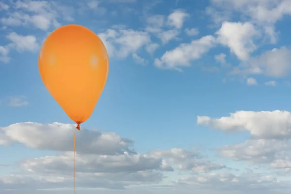 Pomarańczowy balon odizolowany na błękitnym niebie z chmurami — Zdjęcie stockowe
