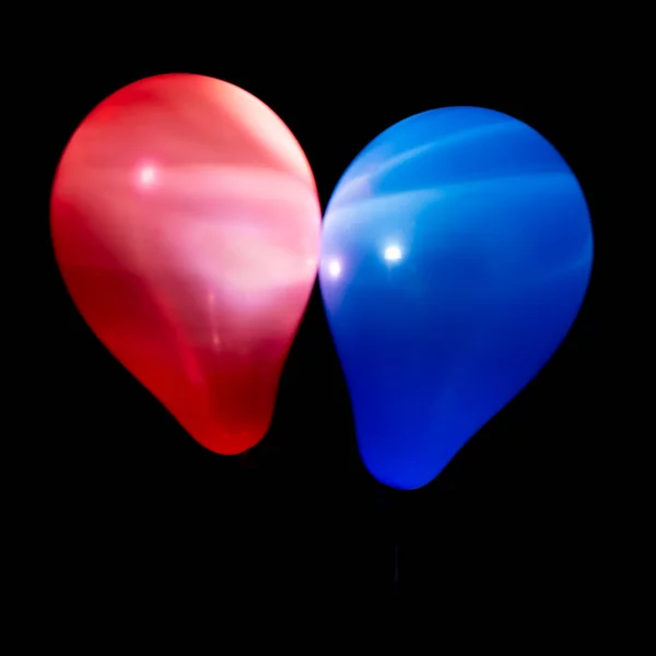 Ballons rouges et bleus illuminés avec LED sur fond sombre — Photo