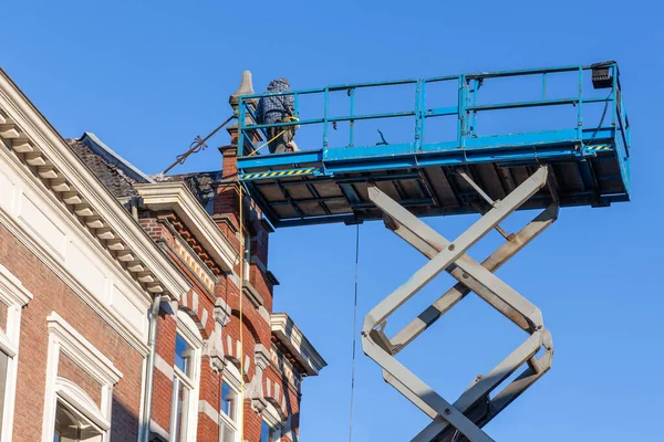 Werkplatform met bouwers die dak historisch Nederlands huis repareren — Stockfoto