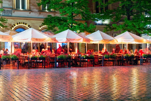 Noite chuvosa com pessoas sentadas em terraços mercado quadrado Cracóvia — Fotografia de Stock