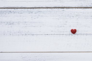 Beyaz ahşap üzerine bir kırmızı küçük kalp