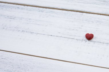 Beyaz ahşap zemin üzerinde bir kırmızı küçük kalp