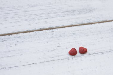 Beyaz ahşap zemin üzerinde iki kırmızı küçük kalp 