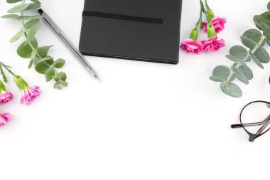 Bebek okaliptüs yaprakları ve pembe karanfil çiçek kopya alanı ile beyaz arka planda siyah defter ve gözlük süslenmiş
