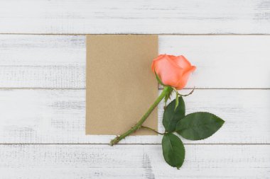 Boş kahverengi kart kopya alanı ile beyaz ahşap arka planda turuncu gül desenli